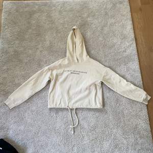 En fin beige croppad hoodie med ett tryck på franska. Från gina tricot 