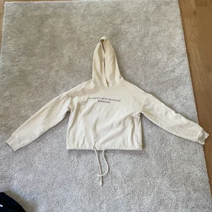 Hoodie - En fin beige croppad hoodie med ett tryck på franska. Från gina tricot 