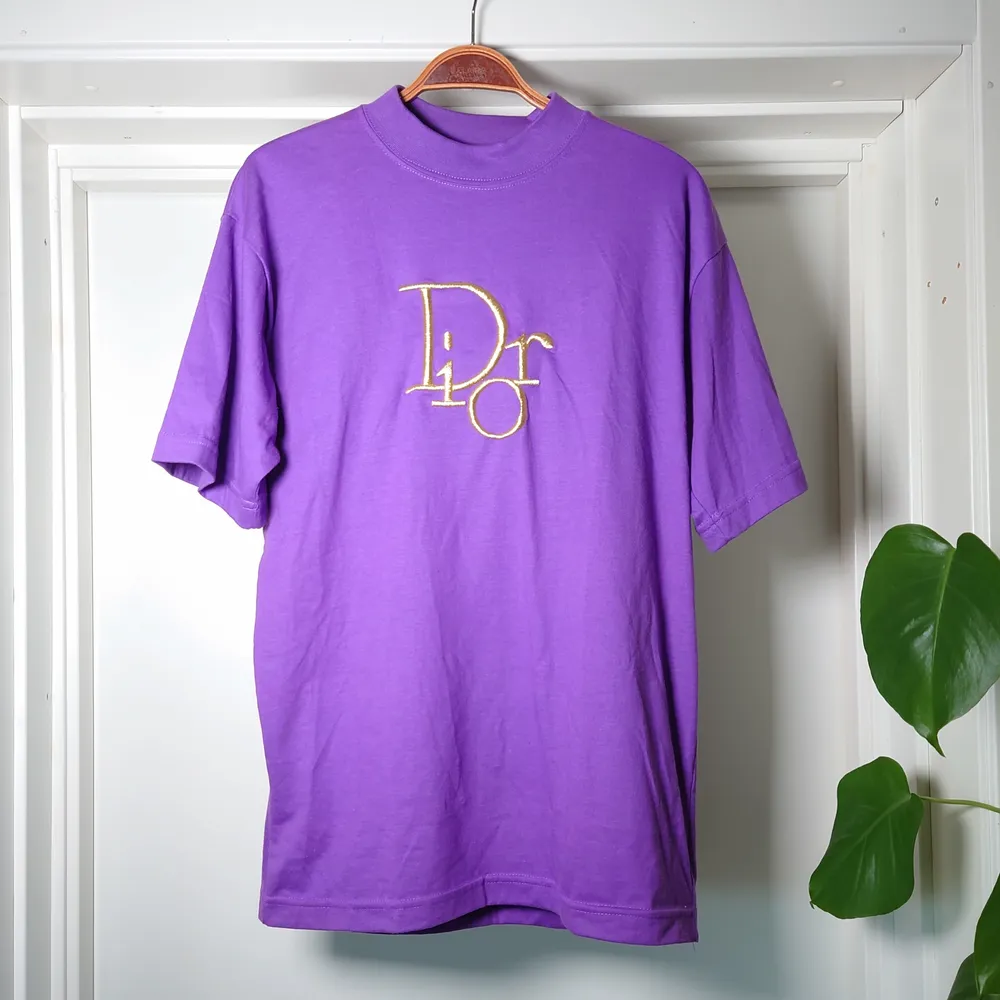 Fejk Dior t-shirt i lila med guldlogga. Ingen storleksmärkning men bör vara M🍀. T-shirts.