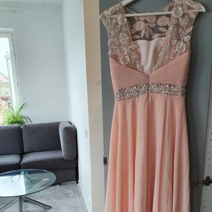 Balklänning / bröllopsklänning  - En lång ljus rosa klänning med diamant liknande pärlor på. Icke genomskinlig och inbyggda kupor finns, perfekt för bal och bröllop. Har använts en gång tidigare och är i bra skickt. Orginala pris, 2 000kr. Kontakta för mer info.