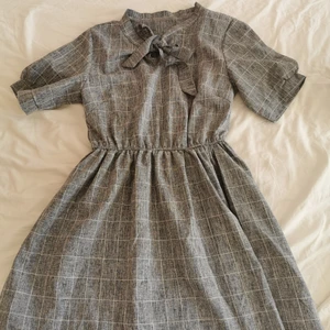 Klänning  - Superfin klänning i grårutit mönster, vid kjol och knytning vid halsen☺️köpt secondhand men i mycket fint skick då den nästan ser ny ut. Står ingen storlek men skulle säga att den passar S-M🌼