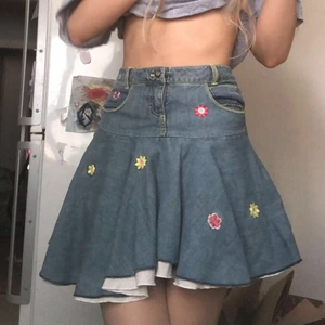 Jeanskjol med blommor  - Använd endast en gång och i superbra skick. Snörning där bak för att justera runt midjan. Superfin men kommer inte till användning. Den går ner precis under rumpan på mig och är i storlek xs. Frakt tillkommer annars möts jag upp i Stockholm<3