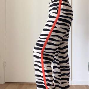 Slutsålda byxor från Lindex. Byxorna är i zebra tyg med en orange/röd detalj längs båda sidorna. Storlek XS. Jag är 162 lång och byxorna passar mig perfekt i längden. 