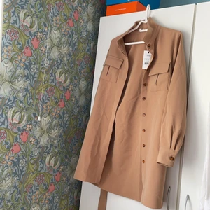 nakd kappa - beige/brun nakd kappa med bälte, storlek 38. aldrig använd och prislapp finns kvar original pris 549kr