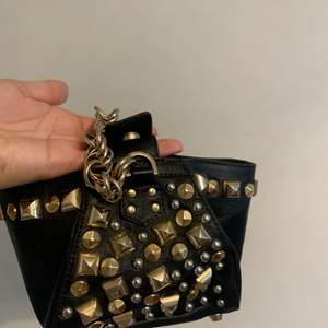 liten handväska i svart (fake) läder med guld och silvriga studs som var designad av Versace för HM, inte min stil längre därför säljer jag den nu (andra bilden är lånad)