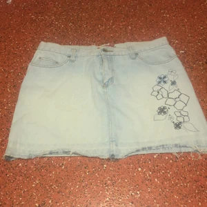 Jeanskjol  - Provat den endast en gång så den är i Bra skick. Den har detaljer av olika blommor under vänstra fickan.  