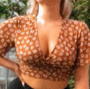 En brun lätt polyester topp med blommor - Detta är en jätte fin topp från pull & bear som jag har köpt på Minorca. Toppen har en bas färg som är en tropisk brun färg med blommor som detalj-mönster. Blommorna är vita med blå-lila färger.                                                                     Original pris 229:-