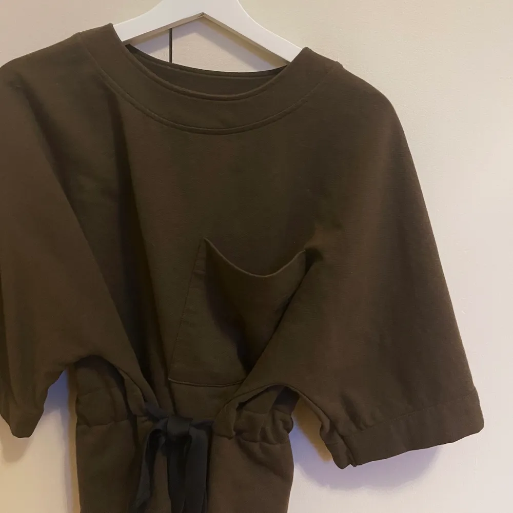 En mörkgrön tshirt i sweatshirt material med knytning i midjan och ficka på vänster sida. Köpt från Zara och är i storlek S. Använd några gånger men är i bra skick. Säljer för 150kr + frakt.. T-shirts.