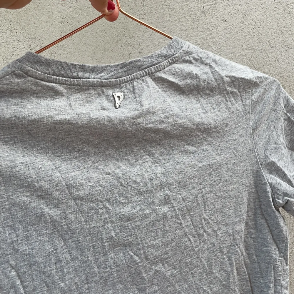 En grå DONDUP med tryck på magen. Helt oanvänd, pga fel storlek. Tröjan har  ett litet märke på baksidan vid nacken. . T-shirts.