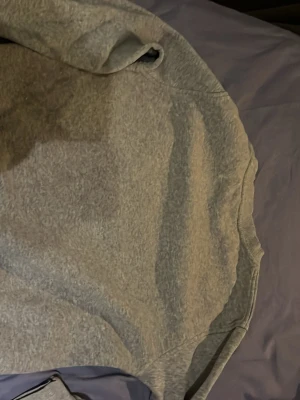 Grå sweatshirt från Nike - Klassisk grå sweatshirt från Nike med rund halsringning och diskret Nike-logga broderad i vitt på bröstet. Tröjan har ribbade muddar vid ärmslut och nederkant, perfekt för en avslappnad och sportig stil.