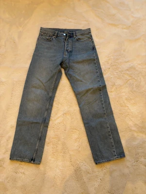 Blå raka jeans från weekday - Säljer ett par blå jeans med rak passform och hög midja. Jeansen har fem fickor, knappgylf och är tillverkade i ett slitstarkt denimtyg. Perfekta för en avslappnad och tidlös stil.