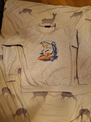 Grå swetshirt raulp lauren - Grå sweatshirt från raulp lauren med en klassisk polo björn. Tröjan har rund halsringning, ribbade muddar vid ärmslut och nederkant samt en avslappnad passform. Perfekt för en chill och lekfull stil.