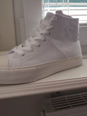 Vita höga sneakers från Guess - Snygga vita sneakers från Guess , aldrig använt . Skick 10/10. Storlek 37