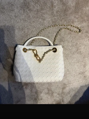 Vit flätad handväska med guldkedja - Säljer en stilren vit handväska i flätad design med guldfärgade metalldetaljer och kedja. Väskan har rundade handtag och en elegant, mjuk form. Perfekt accessoar för dig som gillar en clean och trendig look. #bottega #veneta #andiamo 