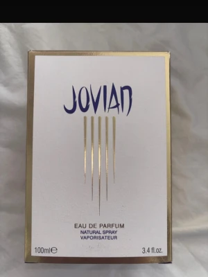 Jovian Eau de Parfum 100ml - Jovian Eau de Parfum i elegant vit och guld förpackning. Flaskan rymmer 100 ml och har en modern design med stilrena guldlinjer på framsidan. Perfekt för dig som vill ha en unik och exklusiv doft i samlingen. Endast testad s