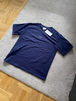 Mörkblå t-shirt från Drôle de Monsieur - Snygg mörkblå t-shirt från Drôle de Monsieur med trycket 'NOT FROM PARIS MADAME' på bröstet. Klassisk passform och rund halsringning. Tillverkad i mjuk bomull som känns skön mot huden. Perfekt för en clean och stilren look.