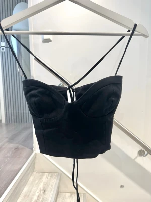 Svart korsettopp med snörning - Svart korsettopp med tunna axelband och snygg snörning i ryggen. Toppen är i storlek 40 men går att justera med banden. Passar mig som har storlek XS/S i toppar💖