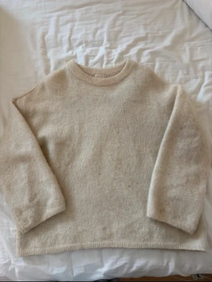 Beige stickad tröja i mohair - Mysig beige stickad tröja med rund hals och ribbade muddar. Tröjan har en rak passform och är tillverkad i en mjuk mohair som känns skön mot huden. Perfekt för kyliga dagar och enkel att matcha med olika outfits. Har vissa fläckar ( visas på bildern) skriv om ni har frågor