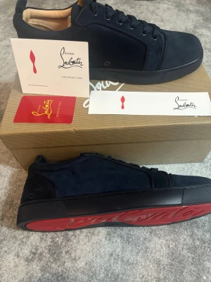 Blåa sneakers från Christian Louboutin utan box  - Snygga blåa sneakers från Christian Louboutin i mocka med klassisk röd sula och diskret logga på sidan. Skorna har snörning och en stilren, låg profil som passar perfekt till streetwear eller en mer uppklädd look. OBS! Utan box 