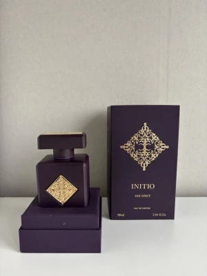 kvitto finns Initio Side Effect Eau de Parfum 90ml  - Lyxig parfym från Initio, Side Effect, i en elegant mörklila flaska med guldfärgade detaljer och matchande ask. Flaskan har en fyrkantig form och exklusiv design med dekorativt mönster. Innehåller 90 ml Eau de Parfum. 