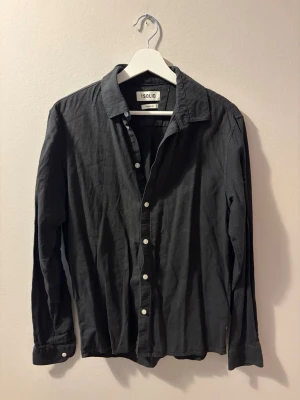Svart linneskjorta från Solid - Stilren svart skjorta från Solid i mjukt linne. Klassisk krage, vita knappar framtill och långa ärmar med knapp vid manschetten. Perfekt för dig som gillar en enkel men snygg look.