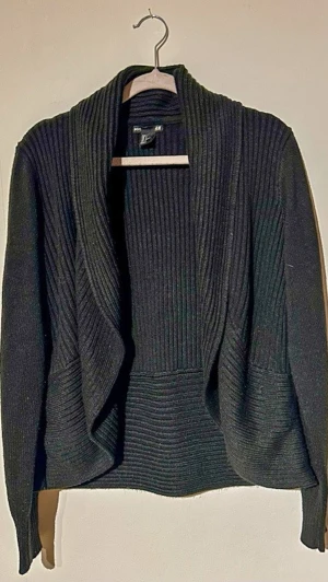 Svart ribbad kofta 🖤 sitter så fint - Ribbad svart kofta från H&M – sjukt clean fit ✨ Figursydd med snyggt fall framtill, perfekt till alla outfits.  • Strl L • Väldigt fint skick • Stretchig & skön  Mått: 48 bust / 55 längd / 61 ärm  Perfekt basic som alltid funkar 🔥