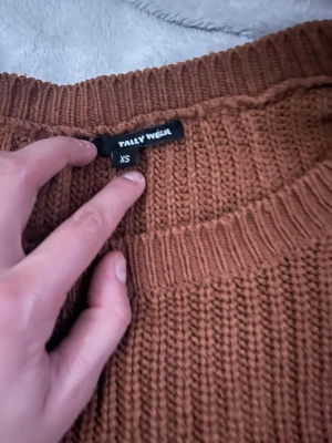 Brun stickad tröja från Tally Weijl - Mysig brun stickad tröja från Tally Weijl i storlek XS. Tröjan har rund halsringning, breda ribbade muddar vid ärmslut och nederkant samt en chunky stickad struktur. Perfekt för kyliga dagar och enkel att styla med jeans eller kjol. Använt 2 gånger 