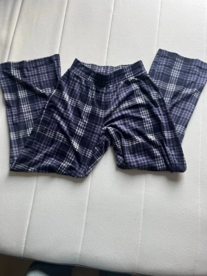 Rutiga pyjamasbyxor från Hunkemöller - Mysiga pyjamasbyxor från Hunkemöller i mörkblått och vitt rutigt mönster. Byxorna har resår i midjan och är gjorda i ett mjukt, bekvämt material som passar perfekt för slappa dagar hemma.