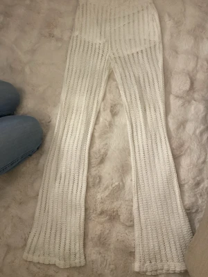 Vita virkade byxor från Bershka, small - Superfina vita virkade leggings från Bershka med lätt utsvängda ben. De har ett snyggt hålmönster och hög midja som går att vika ner resår i midjan. Innershorts. Storlek S