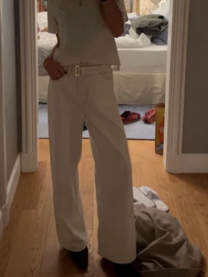 Vida vita jeans med bälte - Snygga vida jeans från GANNI i offwhite med tillhörande bälte och hög midja. Jeansen har raka ben och klassiska fickor fram och bak.  Materialet är denim i bomull. Knappt använda pga fel storlek.