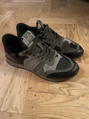 Valentino rockrunners garavani - Snygga sneakers från Valentino med militärgrönt camo-mönster, svarta detaljer och robust sula. Skorna har lågt skaft och är tillverkade i en mix av textil och läder. Perfekta för dig som gillar streetstyle och exklusiva märken.