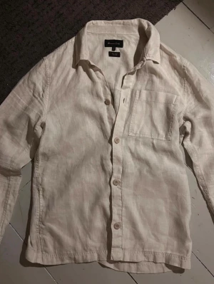 Beige/cream linne overshirt Massimo dutti - Säljer en stilren beige/cream overshirt från Massimo dutti i 100%  linne. Overshirten har klassisk krage, bröstficka och knappar framtill. Perfekt för dig som gillar en avslappnad men snygg look. Passar till både jeans och shorts och sjukt najs på sommar kvällar. Hör av er vid funderingar!