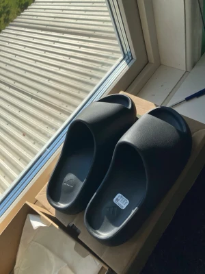 adidas Yeezy Slide Onyx – EU43 / US9 – - Beskrivning: Säljer mina Yeezy Slide Onyx i storlek EU43 / US9. Sjukt clean par och väldigt bekväma. Endast testade/fint skick.