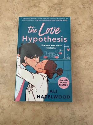 The Love Hypothesis av Ali Hazelwood - Romantisk och charmig roman på engelska med blå och rosa omslag. Boken har illustration av två personer i labbrockar som kysser varandra, med kemiska kolvar i bakgrunden. Perfekt för dig som gillar feelgood och smarta kärlekshistorier.