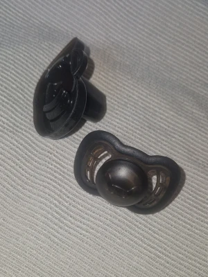 Napp - Helt ny stilren svart napp tillsammans med sitt tillhörande skyddsfodral från det svenska varumärket Herobility. Nappen är en Herobility Pacifier. Den kännetecknas av sin ergonomiska sköld med de patenterade, mjuka gummikanterna och de stora lufthålen som minskar irritation på barnets hud.