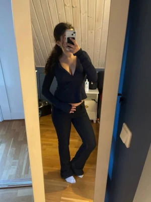 Mörkblå omlottopp med v-ringning - Snygg mörkblå omlottopp med djup v-ringning och långa ärmar. Toppen har en croppad passform och markerad midja som ger en trendig siluett. Perfekt att styla med höga jeans eller kjol för en cool look.