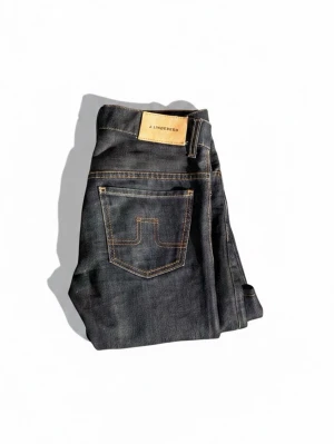 Mörkblå jeans från J.Lindeberg - Snygga mörkblå jeans från J.Lindeberg med klassisk femficksmodell och kontrastsömmar. Jeansen har raka ben och en patch med logga bak i midjan. Perfekta till en avslappnad stil och tillverkade i slitstarkt denimtyg.pris går att diskutera 