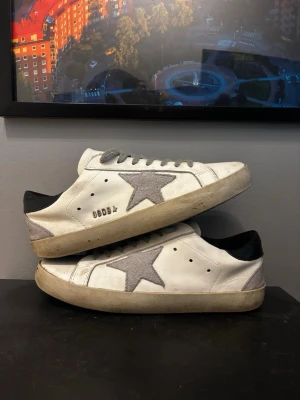 Golden Goose Superstar /42:or - Säljer ett par vita Golden Goose Superstar sneakers med grå mockastjärna på sidan och grå skosnören. Storlek 42! Knappast använda. Obs (En re.plika av mycket hög kvalitet!)