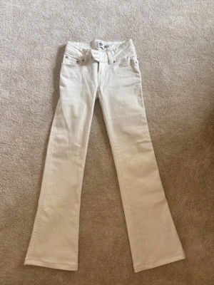 Vita bootcut jeans från 157 - Snygga vita bootcut jeans från 157 med klassisk femficksdesign och dragkedjegylf. Jeansen har utsvängda ben och är tillverkade i ett mjukt denimtyg som känns bekvämt hela dagen. Perfekta för dig som gillar en retroinspirerad look. De är helt nya! Endast testade och nypris är 400
