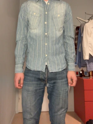 Jättesnygg skjorta från Levi's - Snygg blå skjorta från Levi's med vita ränder och två bröstfickor med knappar.  Cowboy stil med väldigt coola detaljer överallt