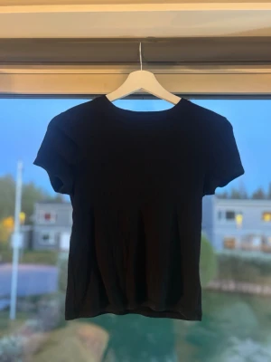 Svart ribbad topp från H&M - En svart ribbad topp från H&M Basic i ekologisk bomull. Modellen har rund halsringning och korta ärmar. Perfekt enkel topp som passar till allt och är superbekväm att bära.