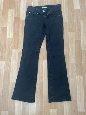 Svarta bootcut jeans från Gina tricot  - Snygga svarta bootcut jeans från Gina tricot med klassisk fickdesign och silverfärgade knappar. Jeansen har utsvängda ben och låg midja.