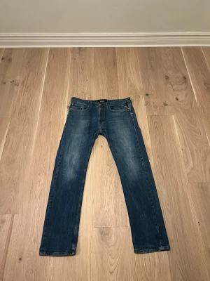 Blå grich jeans från reply  - Säljer ett par klassiska blå jeans från replay Jeans med rak passform och snygga slitningar. Jeansen har fem fickor, knappgylf och är tillverkade i denim. Perfekta för en avslappnad och trendig stil.
