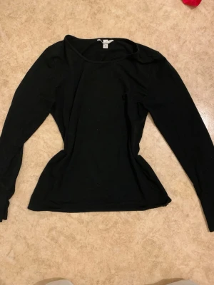Svart långärmad topp H&M - En enkel och stilren svart långärmad topp från H&M. Modellen är figurnära med rund halsringning och mjukt, stretchigt material som passar perfekt till många olika looks.