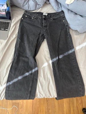 Svarta raka jeans  - Snygga svarta jeans med rak passform och klassisk femficksdesign. Jeansen har låg midja och är tillverkade i ett robust denimtyg. Perfekta för en avslappnad och trendig look.
