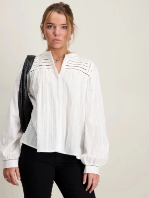 Vit blus från Sofie Schnoor med broderade detaljer - Stilren vit blus med lång ärm och broderade detaljer vid axlar och ärmslut. Blusen har en avslappnad passform, lätt v-ringad hals och är tillverkad i ett tunt, luftigt tyg som ger en skön känsla. Perfekt att matcha med svarta byxor för en clean look.