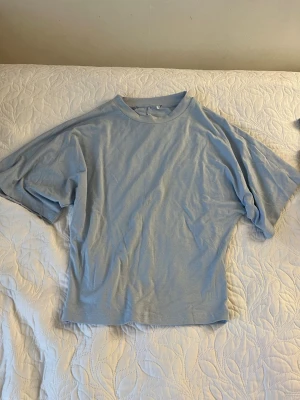 Ljusblå oversized t-shirt - En ljusblå oversized t-shirt med rund hals och korta ärmar. T-shirten har en avslappnad passform och är tillverkad i ett mjukt material som känns skönt mot huden. Perfekt för en chill och stilren look.