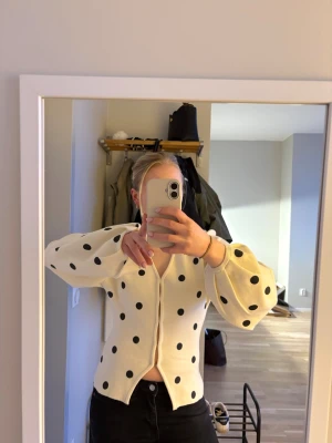 Vit kofta med svarta prickar - Säljer en söt vit trendiga koftan från Gina med svarta prickar och ballongärmar. Koftan har v-ringning och knäppning framtill. Ny utan prislapp, ändast testad