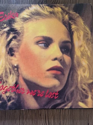 Erika - Together we're lost vinyl - Vinylsingel med Erika, titeln 'Together we're lost' på A-sidan och 'Second of eternity' på B-sidan. Omslaget har ett färgstarkt porträtt med blonda toner och röd text. Producerad av Ljunggren Almqvist och utgiven av Lionheart Records.ä