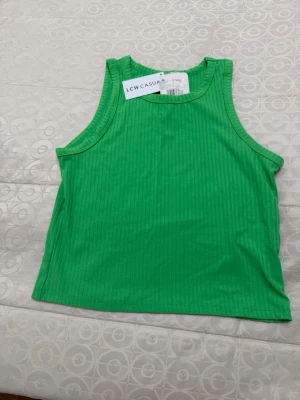 Grön ribbad linnetopp LCW CASUAL - Snygg grön ribbad linnetopp från LCW CASUAL. Toppen är ärmlös med rund halsringning och croppad passform, perfekt för en avslappnad och trendig stil. Enkel att matcha med jeans eller kjol för en cool look.